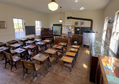 The interior of a historic school is filled with rows of desks