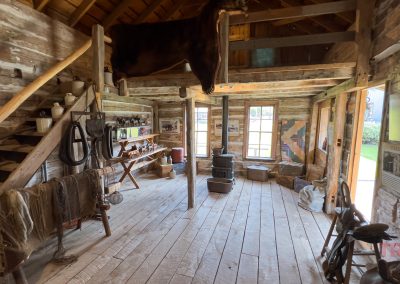 The wood-clad interior of a historic stage coach stop has has tack and saddles on display