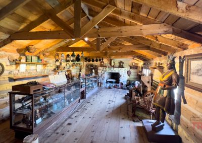 The wood-clad interior of a historic store has shelves and cases with goods of all kinds