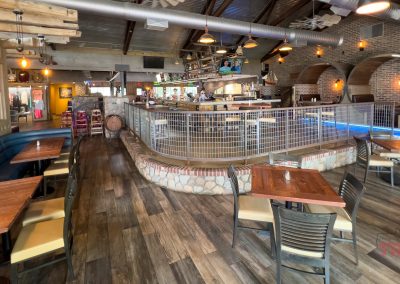 The interior of a large restaurant with brick walls, wood floors and metal accents.