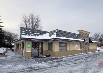The yellow brick exterior of a restaurant in a frosty parking lot
