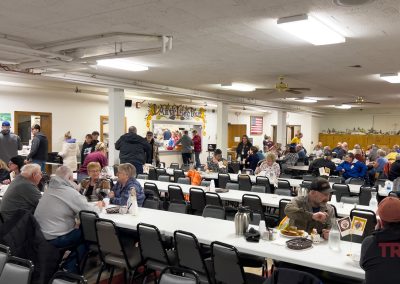 The interior of a church basement with diners sitting at banquet tables