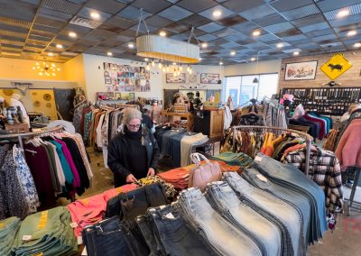 A woman browses the interior of a women's boutique with racks of clothes.